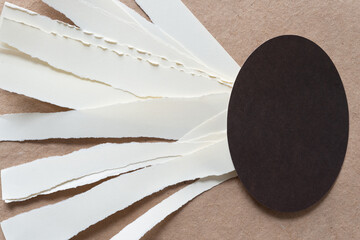 torn paper ribbons and dark brown paper oval on plain brown paper
