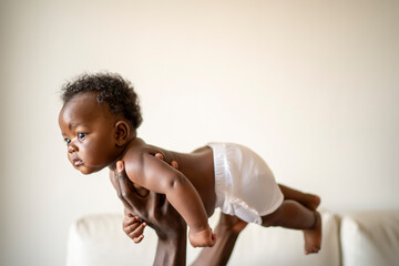 African American baby held in the air by his father in his arms