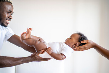 African American baby held in the air by his parents on white background