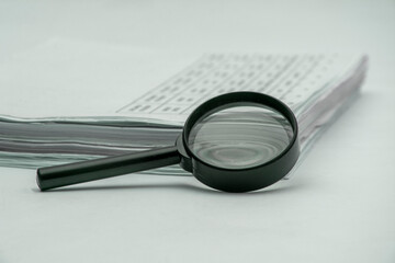 Background view of stacks of papers and magnifying glass on white background
