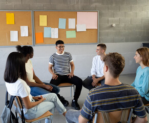 Group of diverse teenage students talking to each other sitting in a circle in a classroom at a school