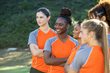 Female soccer team. The women players work together as a team in a group of five wearing matching orange jerseys. 