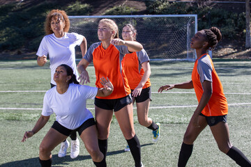 Female soccer players play in an intense and competitive game on the field outside. 