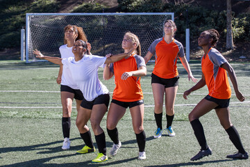 Female soccer players play in an intense and competitive game on the field outside.