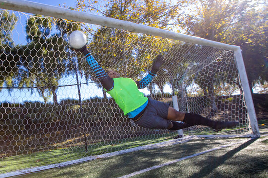Athletic man attempts to block a goal. The soccer player is a goalie in front of the net during a game. 