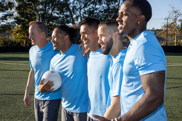 Group of five men on a soccer team. The players are standing proudly together in a blue uniform on the field. 
