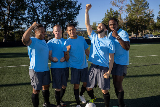 Group of five men on a soccer team. The players are standing proudly together in a blue uniform on the field. 