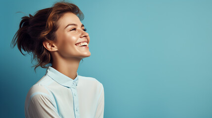 Portrait of young european fashionable female model, shot from the side, smiling, looking to the side, blue background - obrazy, fototapety, plakaty