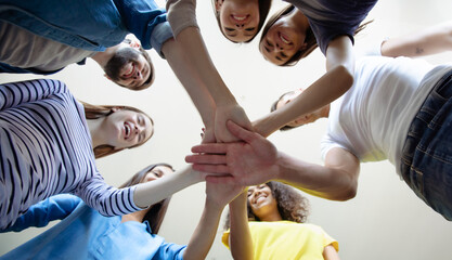 Down view on hands together. Group of happy modern people at work. Start up business team are holding hands together in circle. Smilings students or friends.