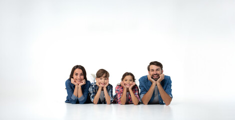 Happy excited beautiful and smiling dad, mommy and them kids sitting on the floor isolated on white...