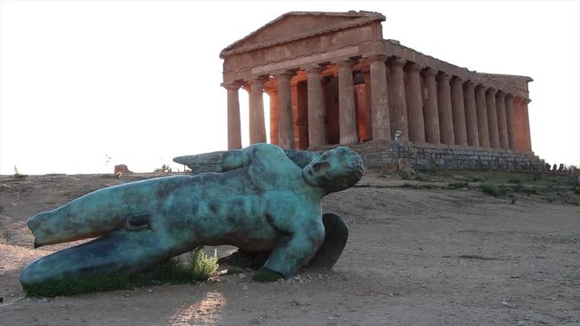 agrigento sicily italy ancient temple of concordia wide shot with damaged broken statue of man lying on its side in foreground