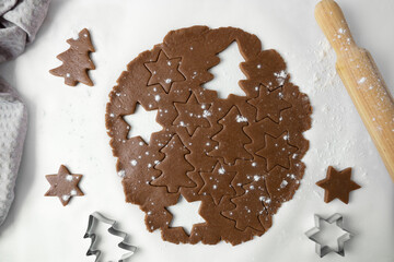 The process of making Christmas cookies. The photo shows the dough, rolling pin and molds for New Year's cookies on a white background. View from above.