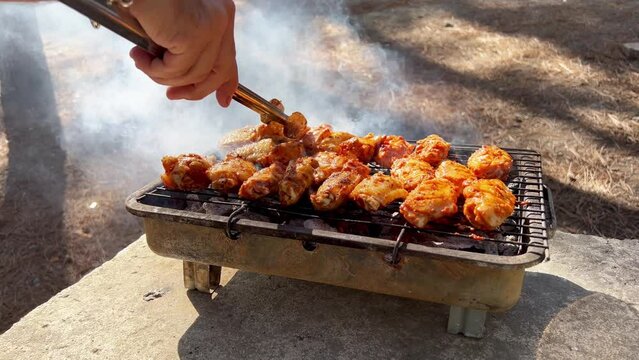 Spicy marinated chicken wings and legs on barbecue. Summer BBQ grill. Grilled raw chicken pieces. Close up
