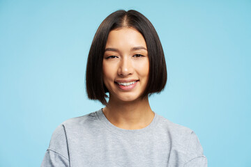 Beautiful asian woman with stylish hairstyle looking at camera standing isolated on blue background