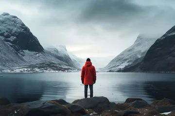 Tuinposter Noord-Europa Man in red jacket standing back by the lake overlooking the mountains with snow, winter nature.generative ai