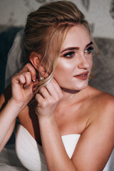 Naklejka premium Wedding earrings on a woman's hand, she takes earrings, bride fees, morning bride, white dress, wearing earrings