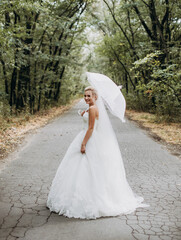 Fototapeta na wymiar Smiling woman in wedding dress holding umbrella
