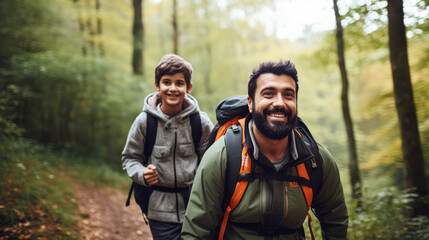 Fototapeta premium smiling son and father walking with backpacks through the forest, nature reserve, hiking, tall trees, blurred background, man, boy, trail, tourists, travel, hike, family, weekend together, child, kid