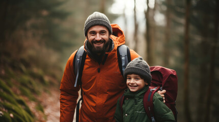 Fototapeta premium smiling son and father walking with backpacks through the forest, nature reserve, hiking, tall trees, blurred background, man, boy, trail, tourists, travel, hike, family, weekend together, child, kid
