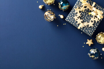 Christmas gift with luxury gold decorations on dark blue background. Elegant Xmas banner template. Flat lay. Top view.