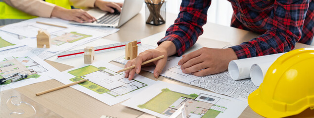 A cropped portrait of professional architect working with blueprint during safety engineer using...