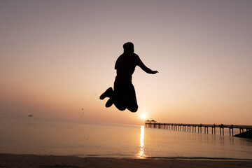 silhouette of a man walking on the beach at sunset