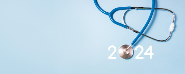 Stethoscope and numbers 2024 on blue background. New Year medical banner. Selective focus, copy...