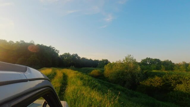 Small green hill and sunlight trees captured from car roof in blue sky in Ub, Serbia
