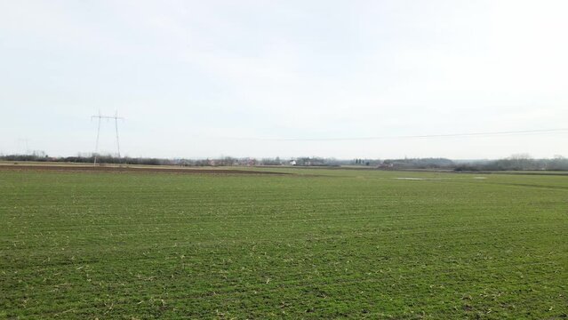 Drone flight above green agricultural fields with village in horizon in Ub, Serbia