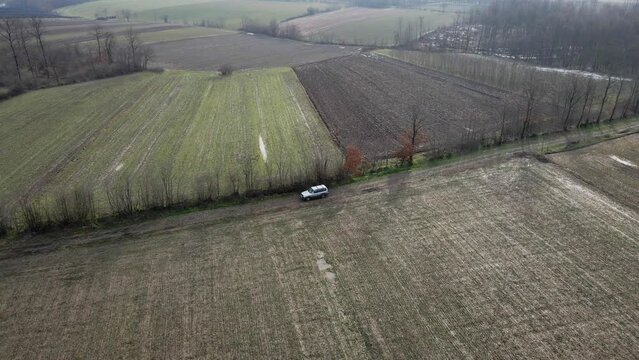 Car driving on dirt road surrounded by agricultural fields in Ub, Serbia