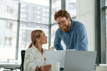 Two diverse business colleagues disscuss biz issue while use laptop in office background