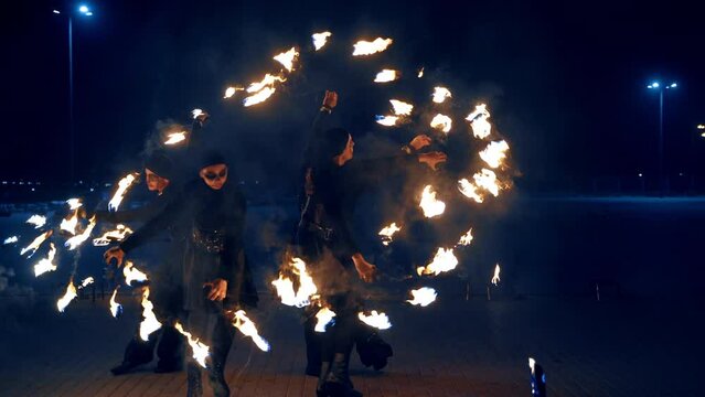Beautiful dance with fire objects. Four people circle holding the burning props at night.