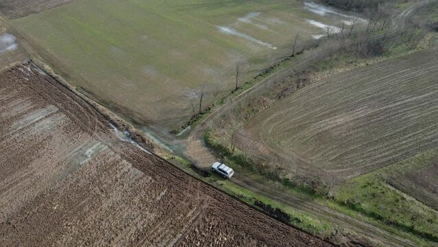 Car drives on dirt road in flooded countryside with few old houses in Ub, Serbia