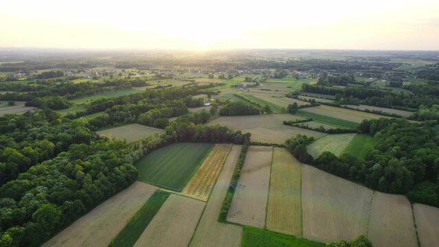 Beautiful sunset above countryside with woods and agricultural fields