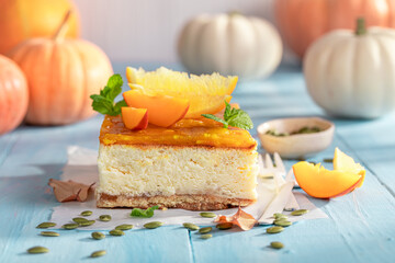 Tasty pumpkin cheesecake decorated with oranges and pumpkins.