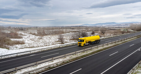 Caravan or convoy of tank trucks in line on a country highway. Yellow Tank truck or cistern on a Highway through the rural landscape. Business Transportation And Trucking Industry.