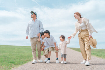 青空の公園を歩く家族・ファミリー・夫婦と子供
