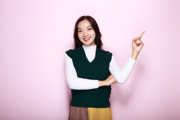 Standing and pointing happily, Portrait of a friendly young woman smiling happily, Beautiful girl on the pink background showing point fingers poses.