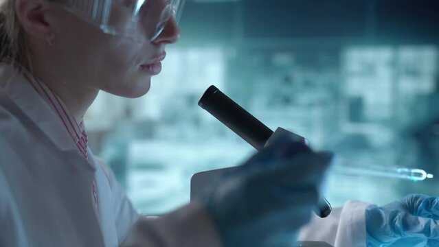 Medical science laboratory. A microbiologist wearing glasses is looking under microscope analyzing sample. Scientist pharmacist working with forensic. Genetic dna research and pharmaceutics concept