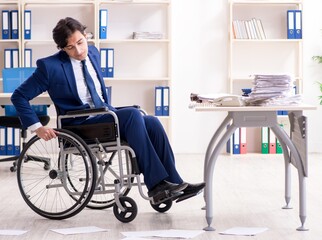 Young male employee in wheelchair working in the office