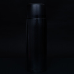 Black thermos cup on black background