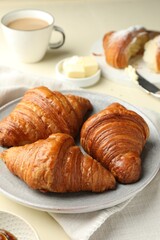Plate with tasty croissants on beige table, closeup