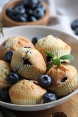 Delicious muffins with blueberries and mint in bowl on table, closeup