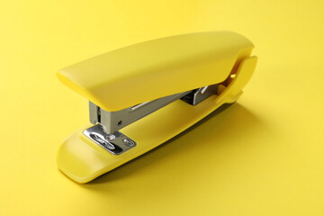 One bright stapler on yellow background, closeup