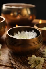 Obraz na płótnie Canvas Tibetan singing bowls and beautiful chrysanthemum flowers on wooden table, closeup