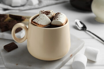Cup of aromatic hot chocolate with marshmallows and cocoa powder on table, closeup
