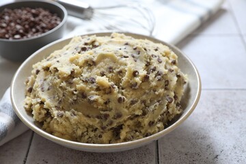 Chocolate chip cookie dough in bowl on tiled table, closeup