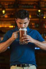 Hombre latino con una cerveza en un bar con colores calidos. con espacio para copy y diseños con expresiones 
