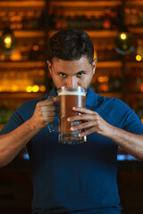 Hombre latino con una cerveza en un bar con colores calidos. con espacio para copy y diseños con expresiones 