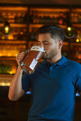 Hombre latino con una cerveza en un bar con colores calidos. con espacio para copy y diseños con expresiones 